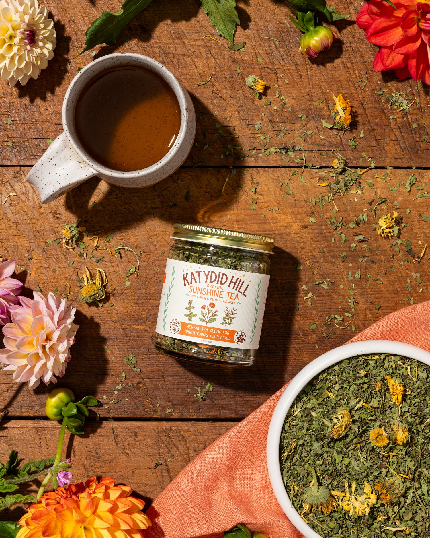 glass jar of sunshine tea on wood background with loose herbs and cup of tea