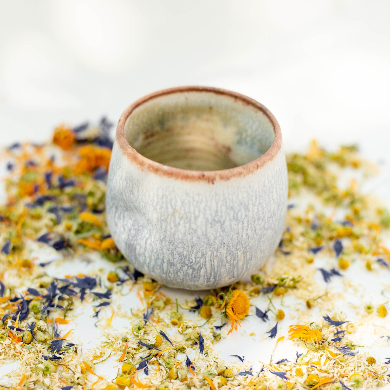 Ceramic tumbler teacup with earthy colors and loose leaf herbal tea