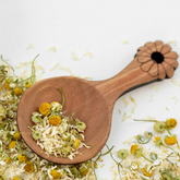 Wooden tea scoop with loose leaf herbal tea chamomile flowers