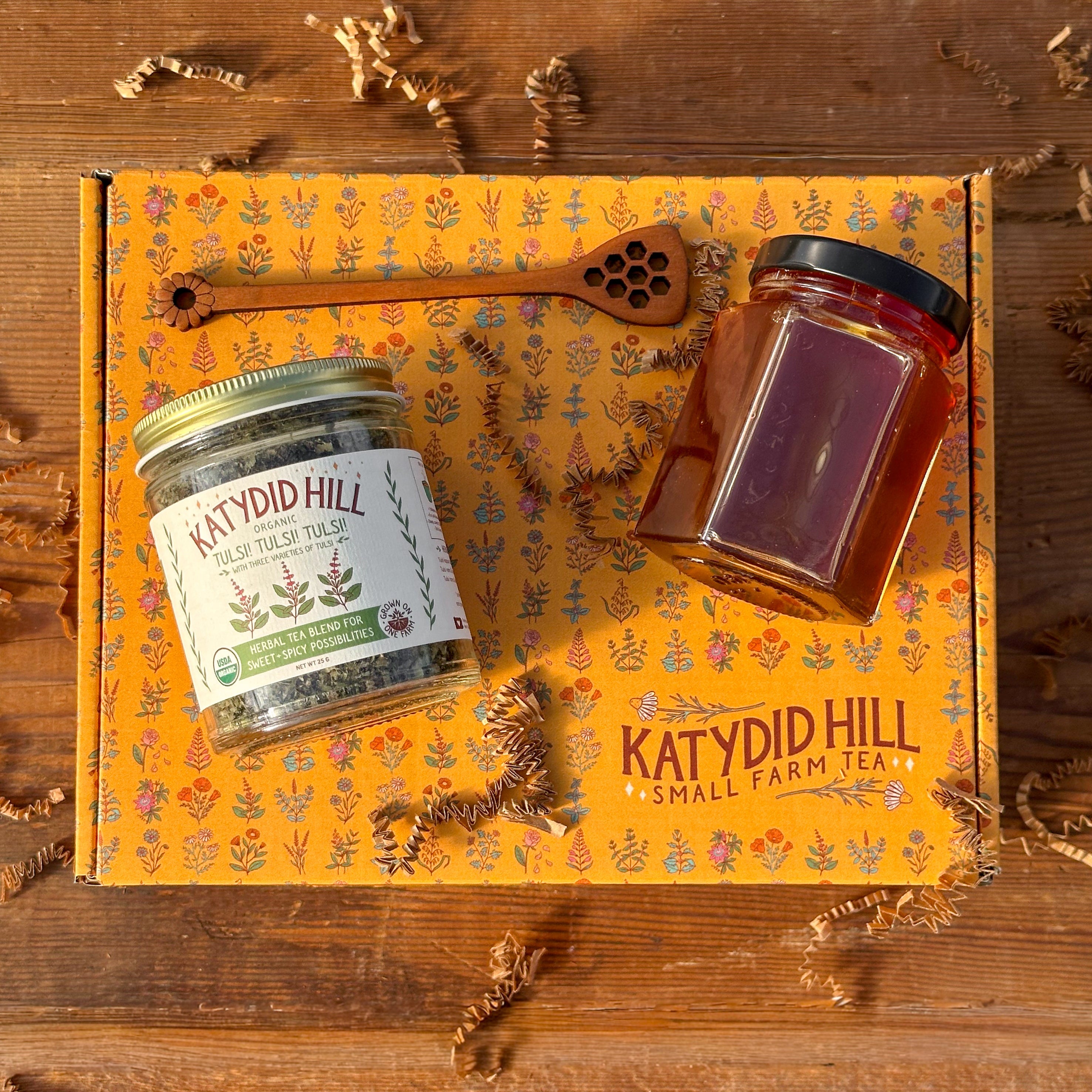 Herbal tea jar, honey jar, and honey stick on top of a gift box