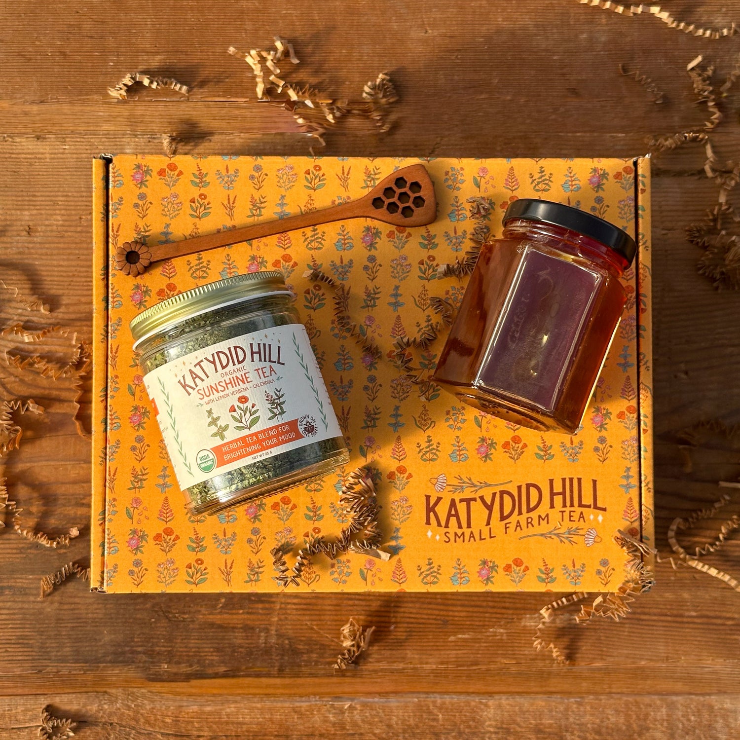 Jar of sunshine tea, honey jar and honey stick on a gift box.