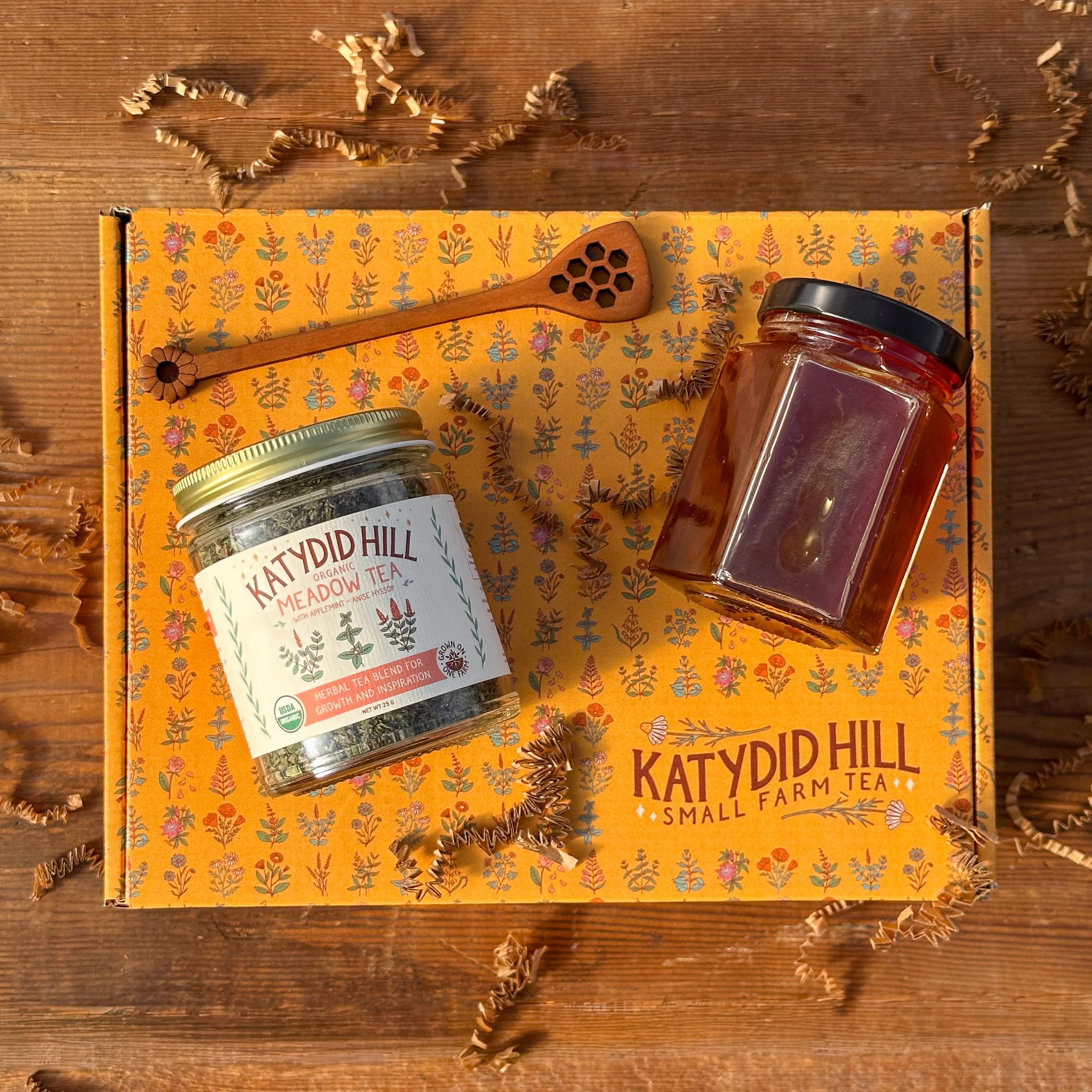 Herbal tea jar, honey jar, and honey stick on top of a gift box