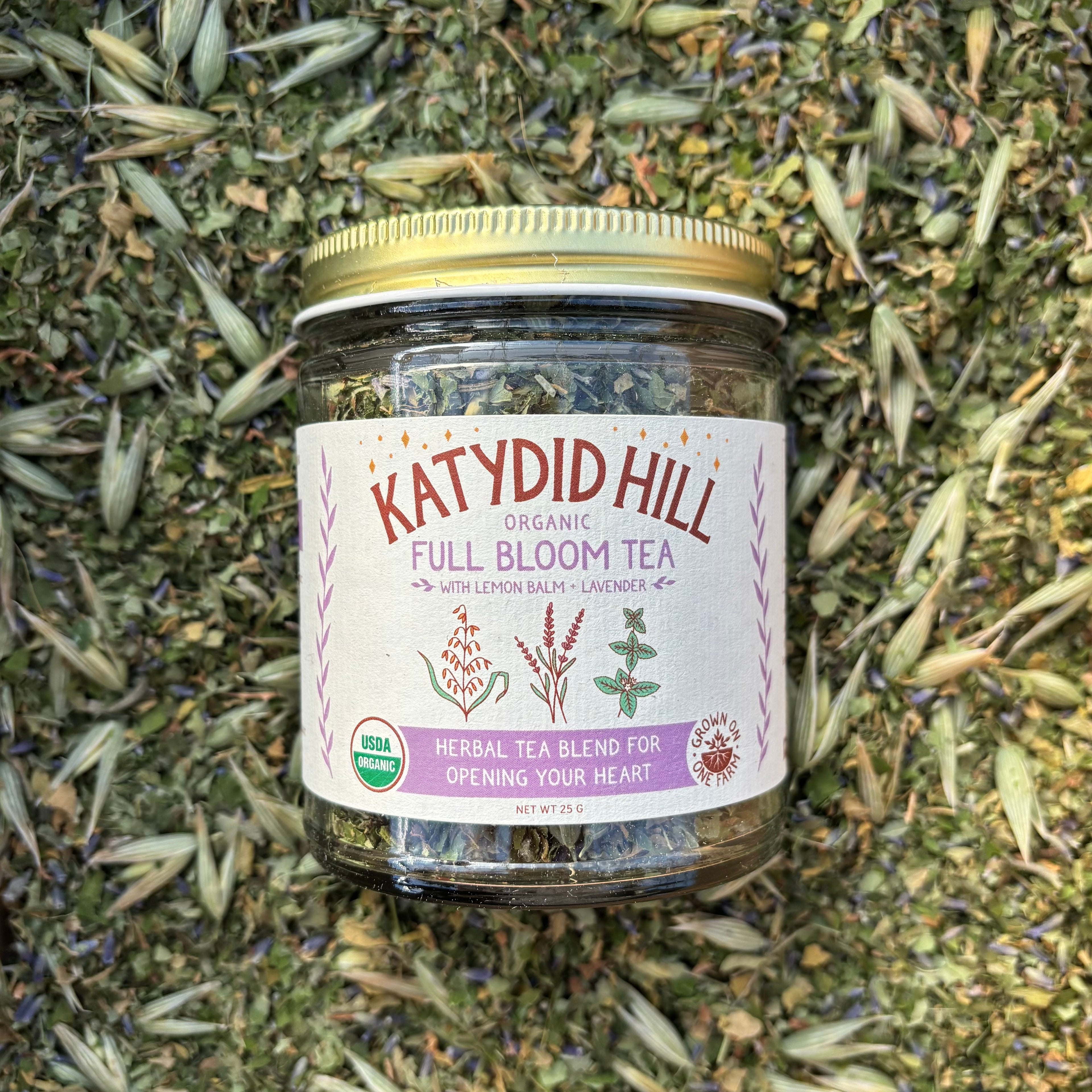 Jar of Katydid Hill Full Bloom Tea on a bed of loose leaf herbal tea