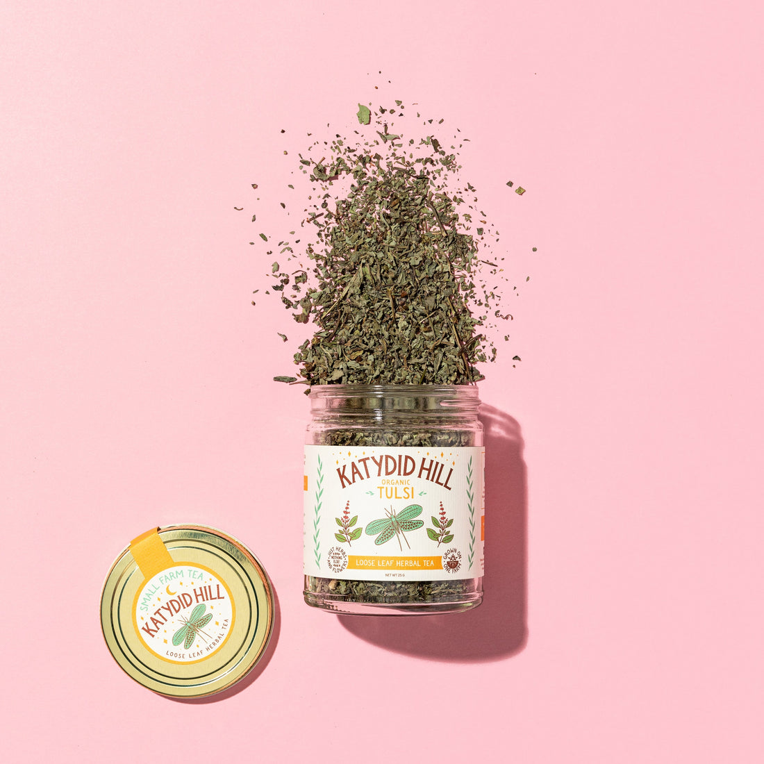 glass jar of tulsi loose leaf tea on to pink background.