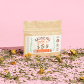sunshine tea sample pack with loose herbs and pink background