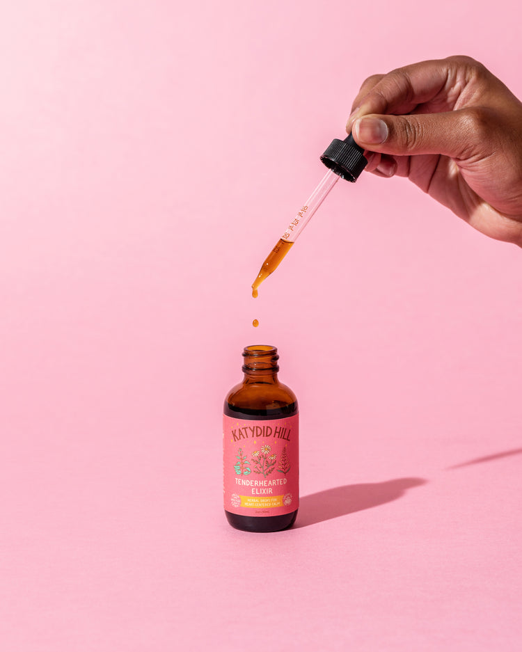 open bottle of tenderhearted elixir on pink background