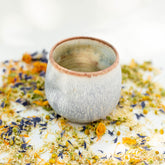 Ceramic tumbler teacup with earthy colors and loose leaf herbal tea 