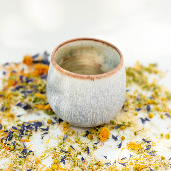 Ceramic tumbler teacup with earthy colors and loose leaf herbal tea 