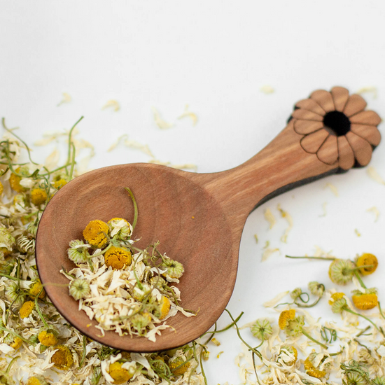 Wooden tea scoop with loose leaf herbal tea chamomile flowers