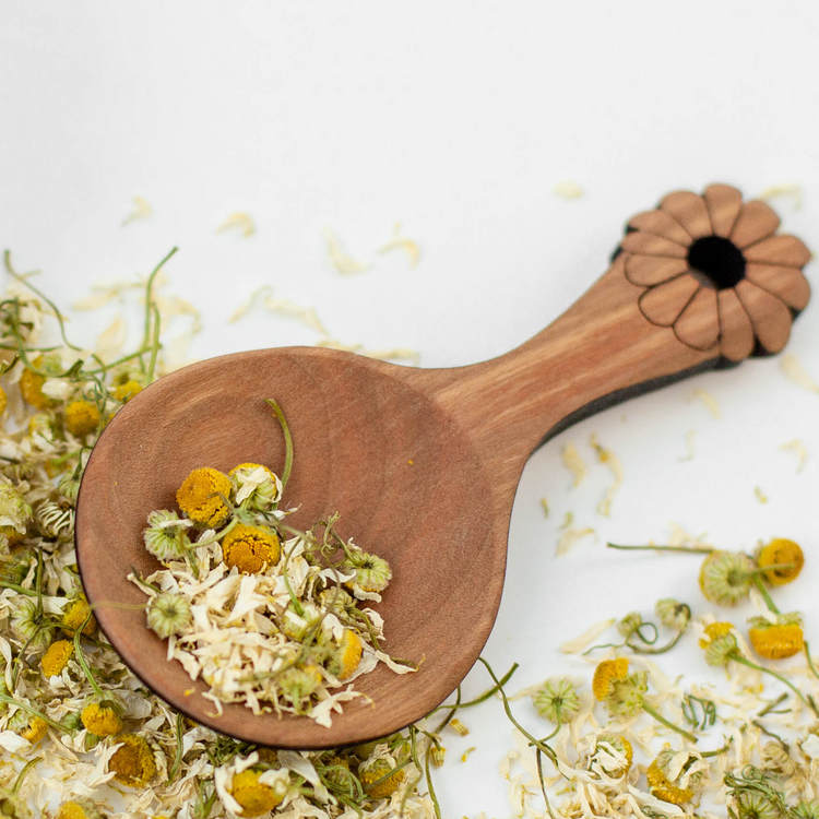 Wooden tea scoop with loose leaf herbal tea chamomile flowers